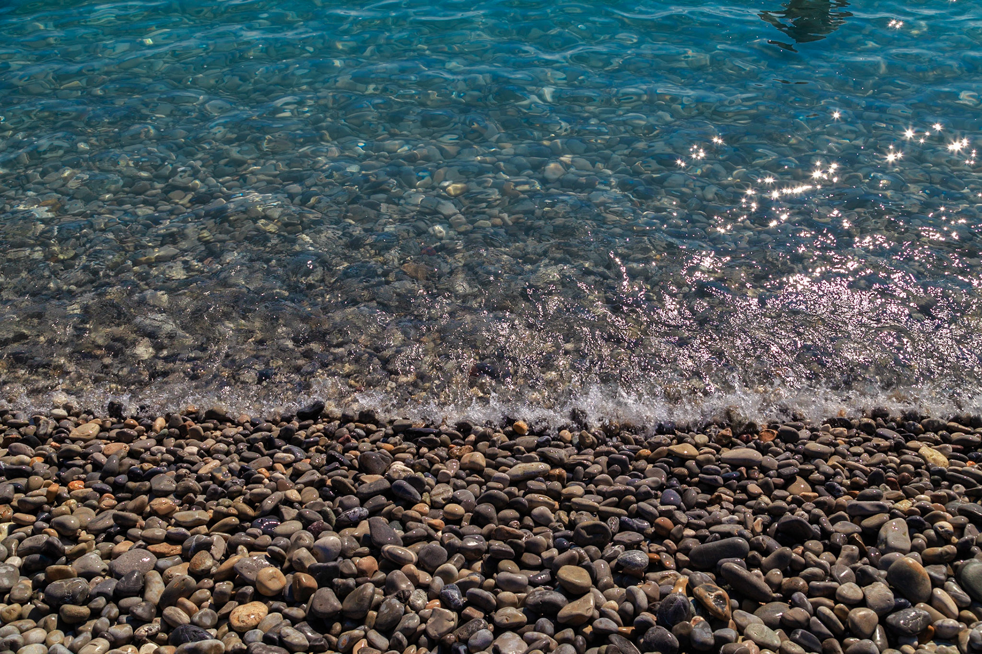 Tides wash a pebble beach during the day.