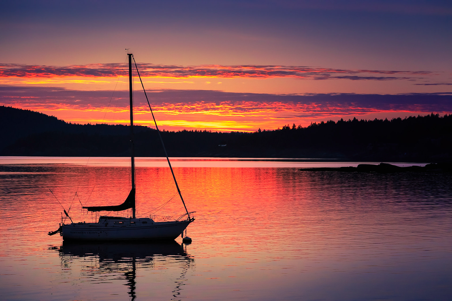 The magical beauty of a golden Sunshine Coast sunset has timeless appeal. If you’re drawn to serene seascapes, you’ll adore this pretty print. It’s a reproduction of a digital photograph by Vancouver photographer, Toby Malek, who earned a Master’s Degree in Media Arts while studying in Vienna, Austria. This print features a sailboat in the water, at dusk, in British Columbia’s picturesque Sunshine Coast region. The twilight beauty and thoughtful composition of this stunning digital photograph will come shining through, whether you choose to have it printed on archival canvas or archival paper. Elegant and inspiring, this gorgeous print will add grace and radiant color to any home or office environment. The warm colours of sunset, from pale coral to rose-pink to saffron to lavender to violet, are the perfect backdrop for the sailboat’s dark silhouette. Further in the background, you’ll see rows of evergreens. If you want texture and dimension, go for archival canvas. It provides 3D appeal. Another option is archival paper, which is crafted from cotton rag. Whatever you choose, you’ll find that this gorgeous print changes the mood of your room in an instant. Perfect for a home or place of business, this striking nature print captures the dazzling beauty of sea and sky.