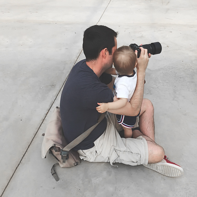 A father shows his infant daughter how to take a photograph